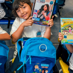 Beneficiario abre su nuevo kit escolar y muestra un cuaderno