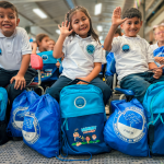 Beneficiarios sonrientes saludan después de recibir su nuevo kit escolar