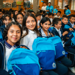 Grupo de beneficiarios sonríen y muestran sus nuevas mochilas