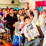 Niños felices saludan a la cámara levantando las manos