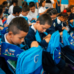 Beneficiarios con curiosidad examinan el contenido de sus nuevos kits escolares.