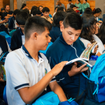Jóvenes estudiantes están sentados leyendo libros y mostrando sus kits escolares