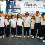 Grupo de beneficiarios sonrientes posan abrazados, en una foto grupal en medio del evento con sus nuevos uniformes