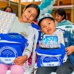 Dos hermanos felices con los útiles escolares recibidos