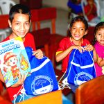 Un niño y dos niñas muestran sus reglaos muy felices