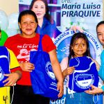 Una madre con sus dos hijos sonríen, al lado de una voluntaria