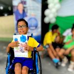 Un niño en silla de ruedas muestra feliz su regalo