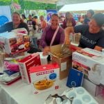 Beneficiarias riendo juntas mientras revisan los utensilios de sus nuevos kits de repostería.