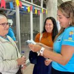 Beneficiaria recibe manilla para ingresar a la jornada por medio de una voluntaria