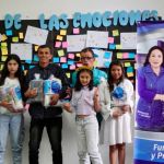 Beneficiarios posan con gran alegría junto al pendón de la Dra. María Luisa después de recibir los kits de aseo