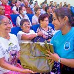 Voluntaría realiza la entrega de morral a una beneficiaria acompañandolo con el gesto de emotividad que acompaño durante toda la jornada