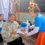Un adulto mayor recibe con brazos abiertos su kit escolar de parte de una voluntaria