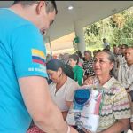 Uno de los voluntarios entrega con entusiasmo un kit de aseo a una mujer invitada especial