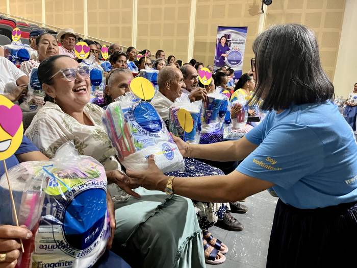 Con gestos de emoción y alegría una mujer adulta mayor recibe en sus manos su kit de aseo