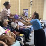 Mujer adulta mayor recibe con gozo su obsequio de manos de una voluntaria