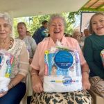Con grandes cornisas tres adultas mayores expresan su emoción al recibir sus kits de aseo