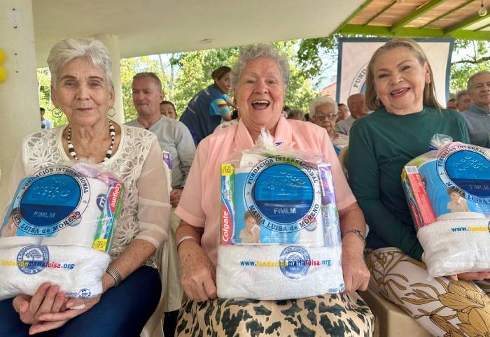 Con grandes cornisas tres adultas mayores expresan su emoción al recibir sus kits de aseo