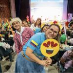 Voluntaria muestra el emoticon de corazón y una gran sonrisa que subraya la emoción positiva que inunda el evento