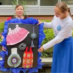 Con talento y color, una beneficiaria muestra artesanía que irradia alegría y habilidad
