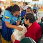 Con sonrisas y atenciones voluntaria realiza la entrega de mercado a una beneficiaria