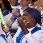 Llena de alegría y gozo una voluntaria sonríe al cantar con sus ojos cerrados