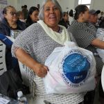 Beneficiaria visiblemente feliz sosteniendo el mercado entregado por la Fundación