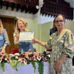Mujer recibe en su mano su diploma como graduada del programa Bienestar para la Persona Mayor
