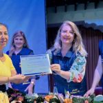 Una mujer recibe en sus manos el diploma como graduada del programa Bienestar para la Persona Mayor