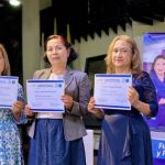 Tres mujeres tras recibir su diploma lo sostienen con emoción