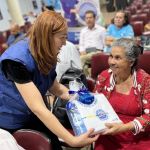 Con cariño una mujer recibe el obsequio que le entrega la voluntaria de parte de la Fundación