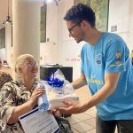 Intercambiando sonrisas una mujer recibe en sus manos un obsequio entregado por el beneficiario