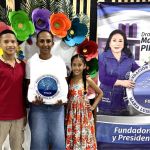 Beneficiarios posan con una gran sonrisa una foto institucional con el pendón de la Dra. María Luisa después de haber recibido el beneficio del mercado