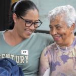 Dos beneficiarias comparten un momento de complicidad y alegria , sus sonrisas genuinas y el gesto de cercanía reflejan el ambiente que se logra crear en la jornada