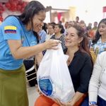 Con sonrisa llena de caliez, voluntaria hace entrega de un beneficio de mercado a una participante reflejando un vínculo de confianza y respeto mutuo