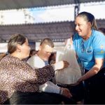 Con una sonrisa cálida y una actitud de entrega, la voluntaria hace entrega del beneficio