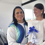 Voluntaria hace entrega de la camiseta institucional de los 25 años a otra voluntaria.