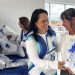 Voluntaria hace entrega de la camiseta institucional de los 25 años a otra voluntaria.