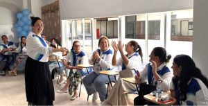 De pie, una voluntaria irradia una alegría absoluta y contagiosa, extendiendo sus manos no solo para compartir un mensaje, sino para abrazar con el alma al equipo.