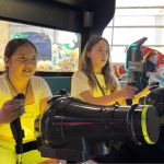 Niñas felices compartiendo en simuladores de disparos
