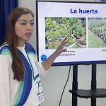 Voluntaria realiza explicación sobre huerta de exterior en suelo y recipientes
