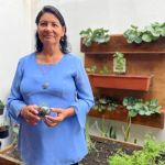 Una estudiante sostiene en sus manos una planta germinada que transplantará en la huerta